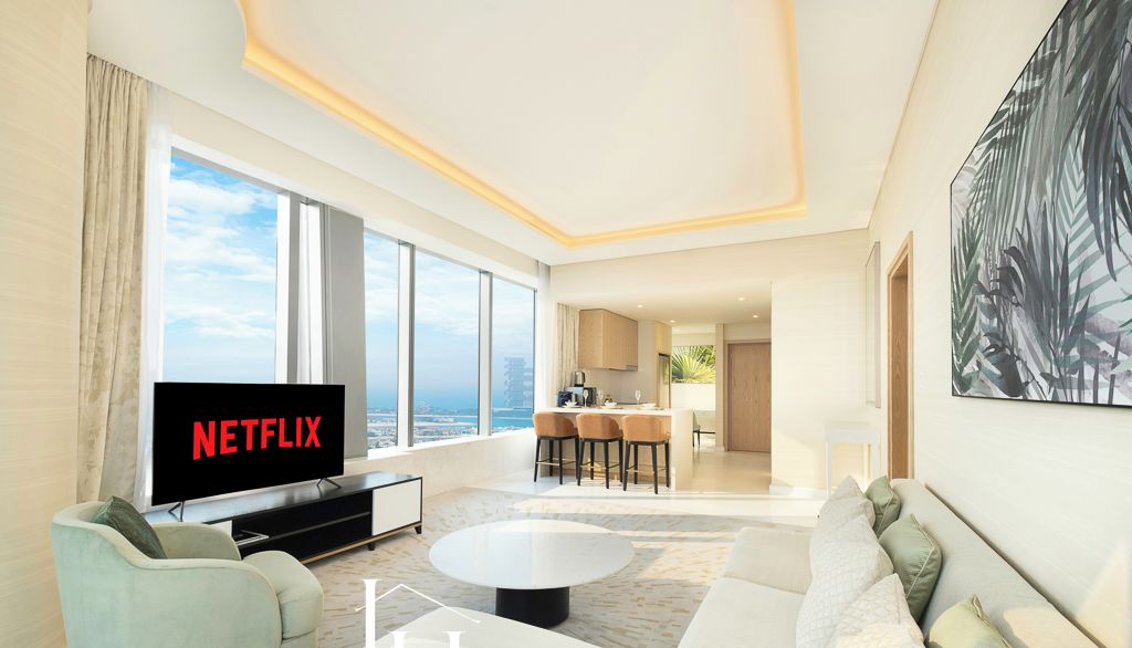 A modern living room with a flat-screen TV, a sofa, a coffee table, and a dining area with chairs.