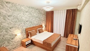 A bedroom with a wooden bed, bedside tables, a nightstand, a wooden dresser, a marble-patterned wall, and a ceiling light fixture.