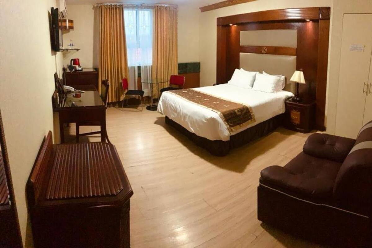 A hotel room with a bed, a desk, a chair, and a small table.