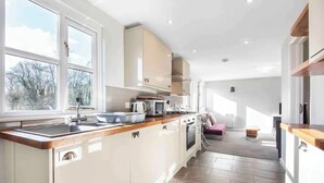 A modern kitchen with a wooden countertop, white cabinets, and a view of the outdoors. - Riverside Stable Cottage, Hunton Yalding Maidstone (Hunton)