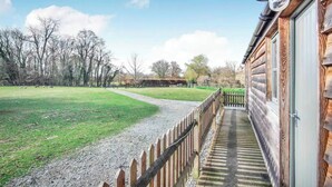 A wooden cabin with a gravel path leading to a grassy field. - Riverside Stable Cottage, Hunton Yalding Maidstone (Hunton)