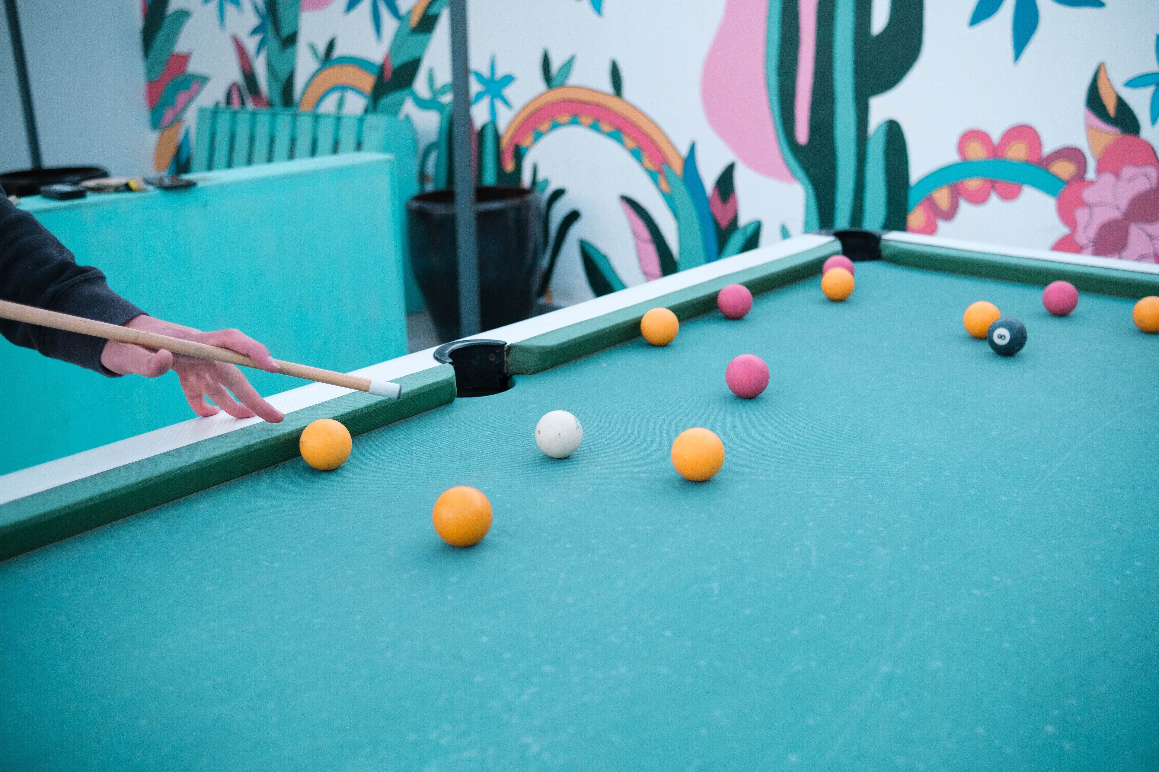 A pool table with balls and a cue stick, indicating a game of pool.