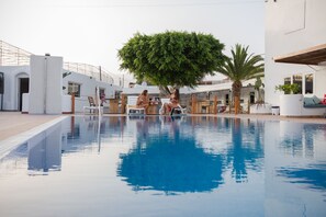 Una piscina con sillas de descanso y un árbol en el centro.