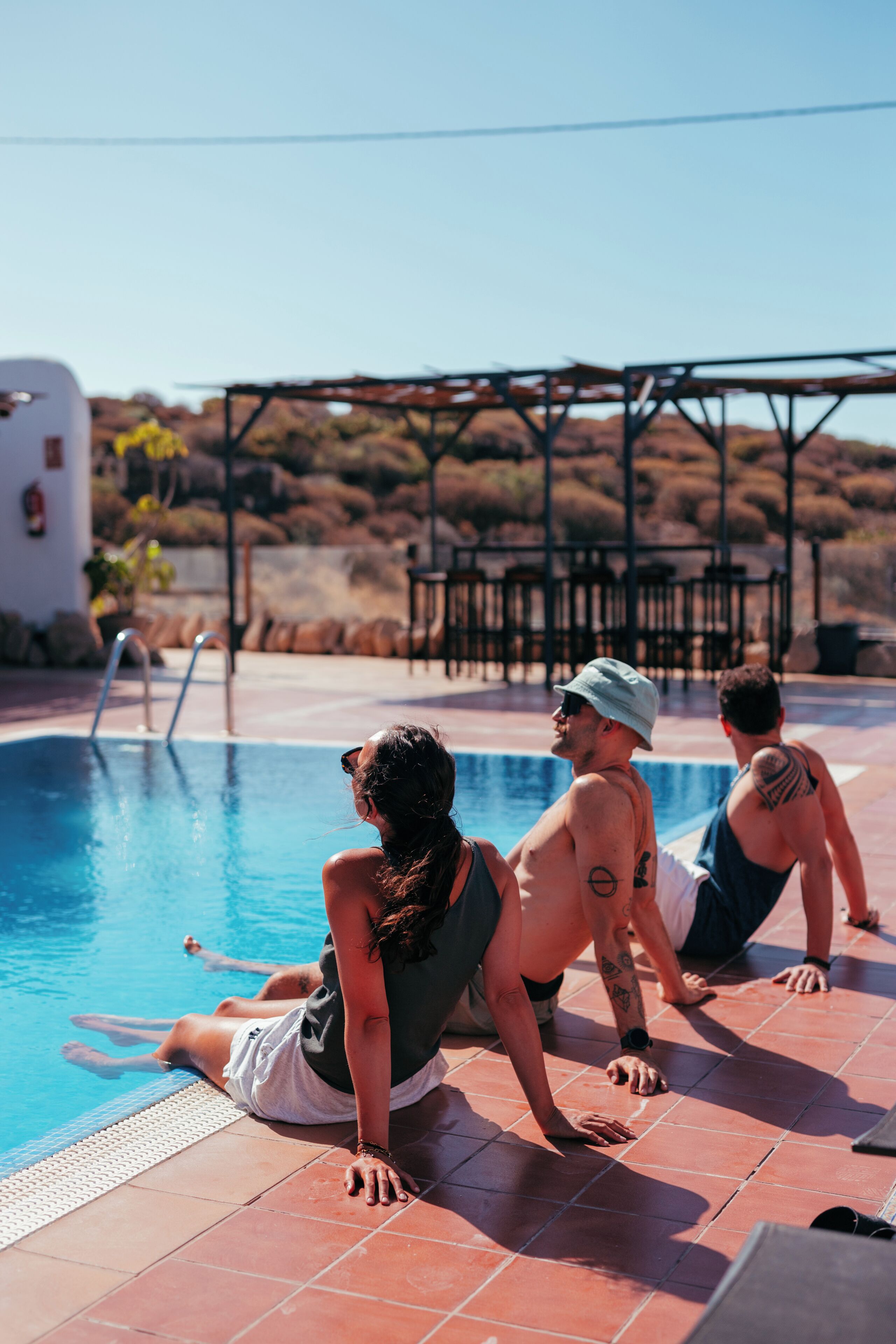 Un área junto a la piscina con vista despejada, un espacio de descanso cubierto y una colina al fondo.