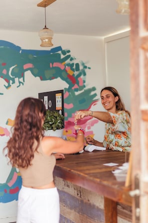 A room with a wooden table, a hanging light fixture, and a wall with abstract art. - The Tree House Hostel (Granadilla de Abona)