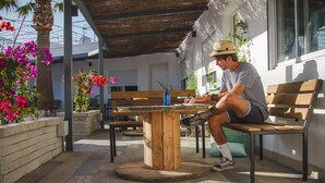 A man sitting at a wooden table with a blue bottle, writing in a notebook. - The Tree House Hostel (Granadilla de Abona)