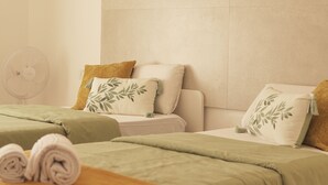 A hotel room with a bed, a bedside table, a fan, and a towel on the floor. - The Tree House Hostel (Granadilla de Abona)