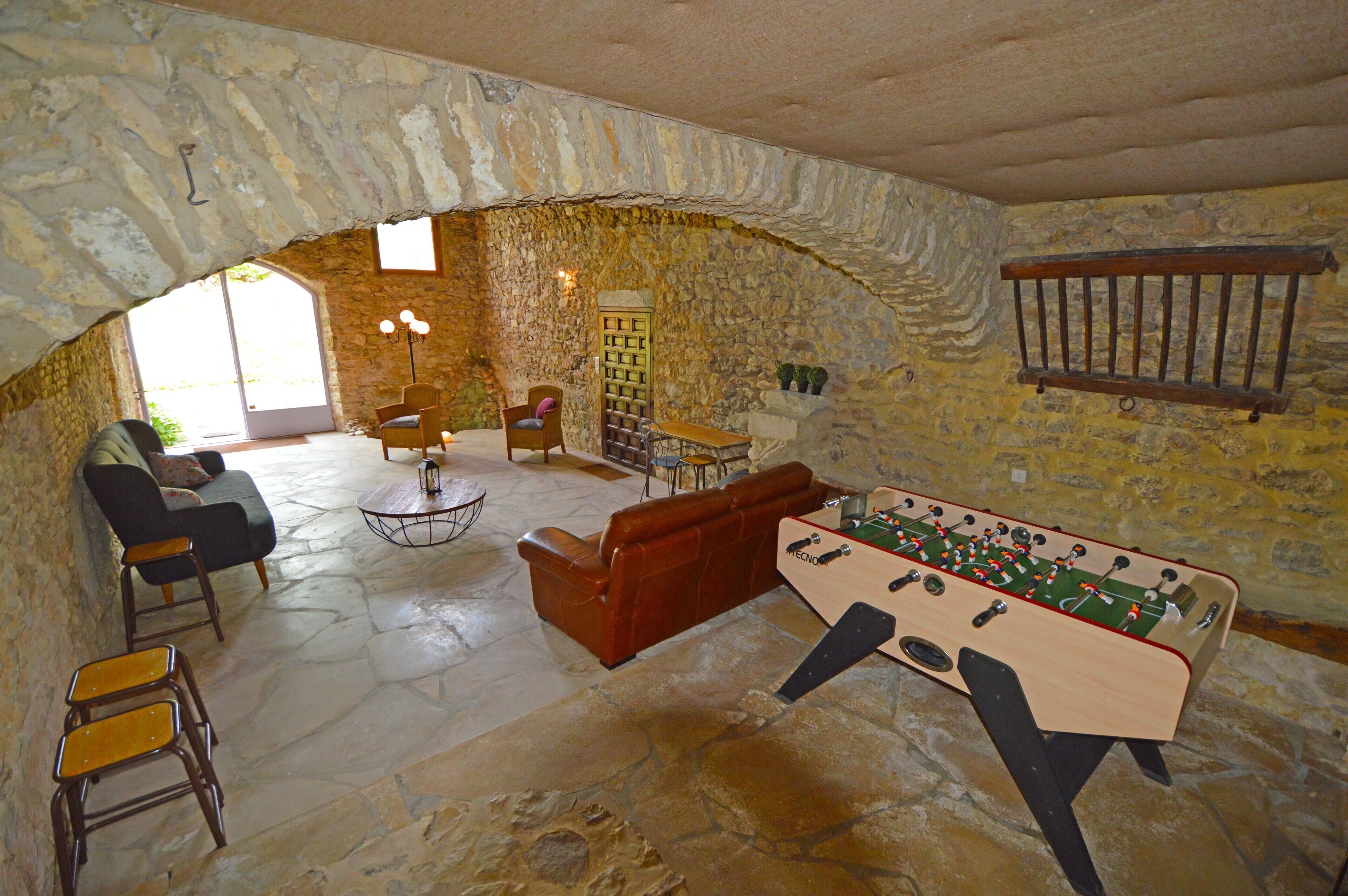 Ein gemütliches Zimmer mit Steinwänden, einem Kicker, einer Couch und einem Couchtisch.