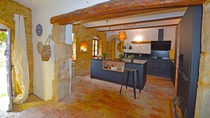 Una cocina rústica con paredes de piedra, vigas de madera y suelo de baldosas.