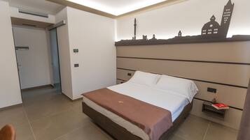 A hotel room with a bed, a city skyline mural, a nightstand, and a door leading to another room.