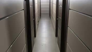 A narrow, well-lit corridor with doors on both sides, leading to individual rooms.