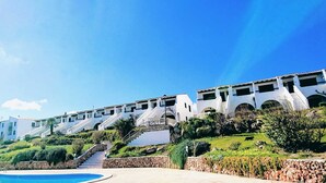 A resort with a pool, multiple-story buildings, and a staircase leading to the upper levels.