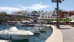 A marina with boats docked, a waterfront promenade, and buildings in the background.