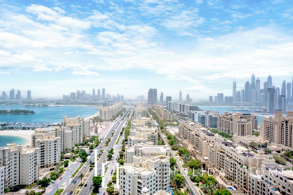 A cityscape with high-rise buildings, a waterfront, and a clear sky.