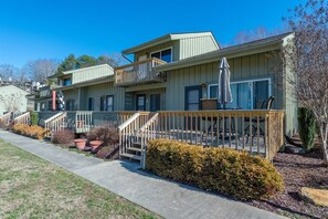 A row of two-story buildings with balconies, a concrete pathway, and potted plants. - Fairway Villa 604 at Rumbling Bald (Lake Lure)
