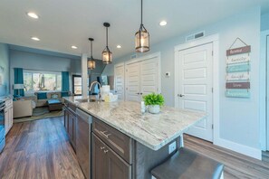 A kitchen with a large island, pendant lights, and a view of the living area. - Fairway Villa 604 at Rumbling Bald (Lake Lure)