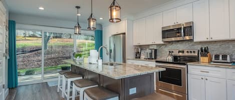 A modern kitchen with a central island, stainless steel appliances, and a view of a landscaped area.