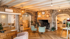 A cozy interior with a stone wall, wooden furniture, and a fireplace. - Demeures & Châteaux - Hôtel de la porte Saint-Malo - DINAN (Dinan)
