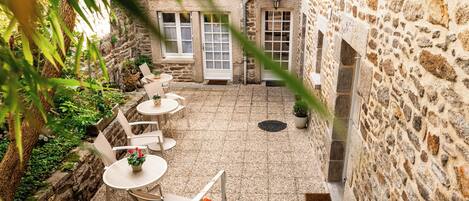A stone courtyard with outdoor seating and a view of a stone building.