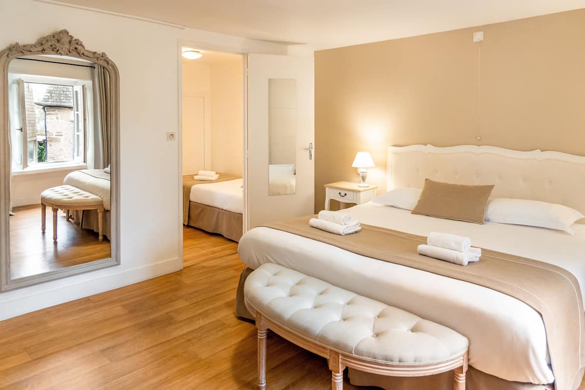 A spacious bedroom with a large bed, a bench, and a mirror.