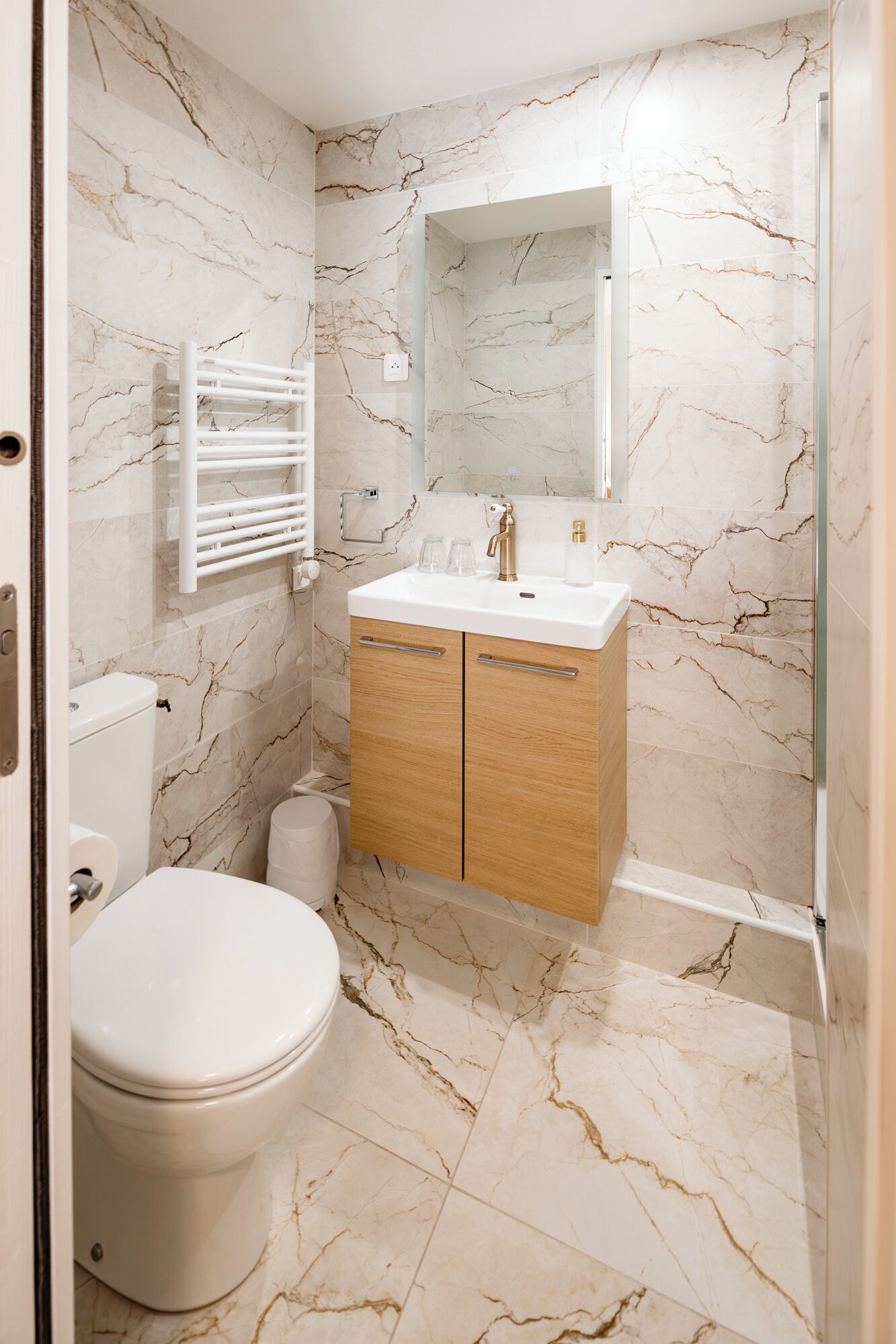 A bathroom with a toilet, a sink with a mirror, and a shower area.