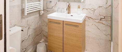 A bathroom with a toilet, a sink with a mirror, and a shower area.