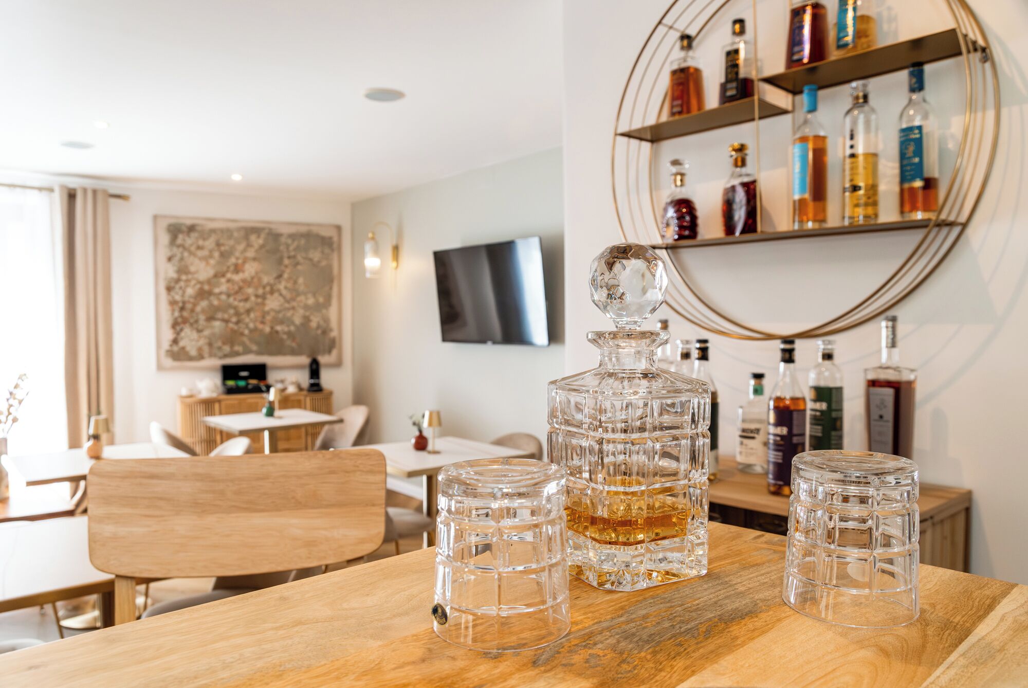 A dining area with a wooden table, clear glass decanters, and a wall-mounted liquor shelf.