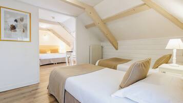 Un dormitorio con dos camas, vigas de madera, un radiador blanco y un cuadro enmarcado en la pared.