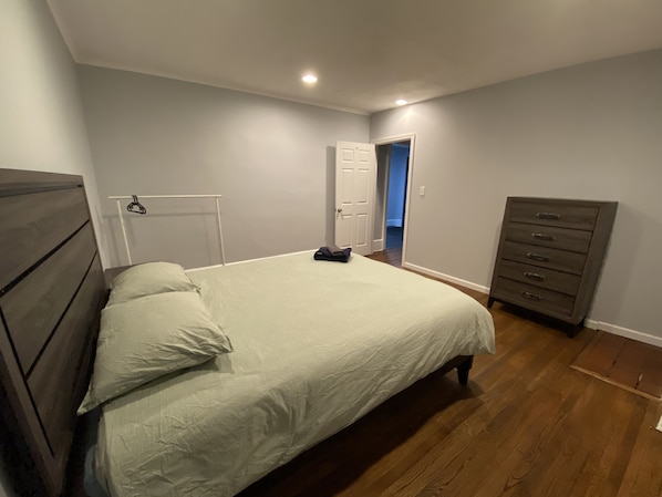Un dormitorio con cama, cómoda y una puerta que da a otra habitación.
