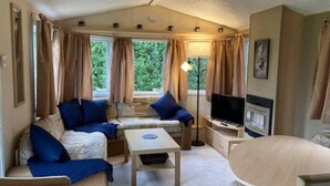 A cozy living room with a sofa set, a coffee table, a TV, and a lamp. - Cosy, Quiet Static Caravan, Mawgan Porth, St Eval (Wadebridge)