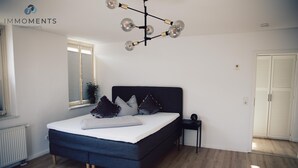 Quarto com cama, mesa de cabeceira, janela e luminária no teto.