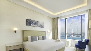 Hotelkamer met een groot bed, een bureau, een stoel en uitzicht op een reuzenrad.