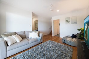 A modern living room with a grey sofa, a blue shag rug, and a painting on the wall.
