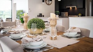A dining table set with plates, bowls, and wine glasses, surrounded by chairs.