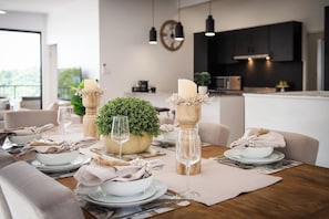 A dining table set with plates, glasses, and a centerpiece of greenery.