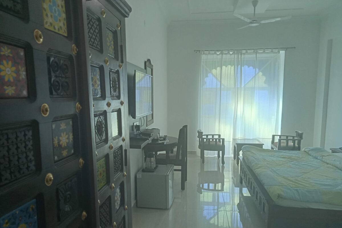 Une chambre d’hôtel comprenant un lit, un bureau avec un ordinateur, une chaise, une petite table et un téléviseur.
