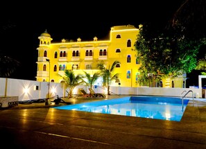 Ein großes Hotel mit Schwimmbad, mehreren Balkonen und einer gut beleuchteten Fassade bei Nacht.