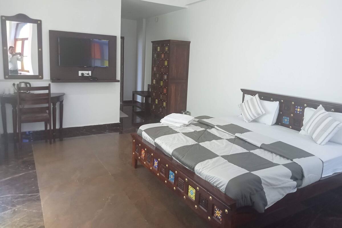 Une chambre à coucher comprenant un lit, un bureau, une chaise, une télévision et une armoire.