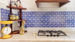Una cocina con estufa a gas, una balanza y un estante con utensilios de cocina.