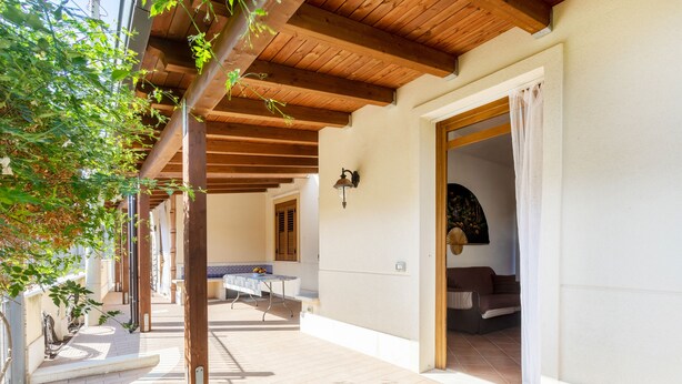 Un espacio al aire libre con un porche de madera, una mesa con sillas y un sofá.