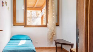 Una habitación pequeña con una cama, una mesa y un ventanal con cortinas.