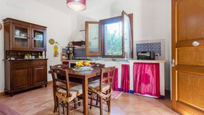 Una cocina con mesa, sillas, un armario y una ventana.