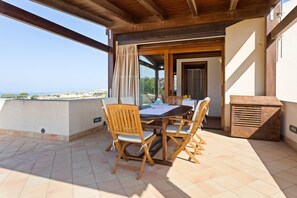 A wooden table and chairs on a balcony with a view of the sea. - Apartment With Panoramic Terrace, Stunning Seaview! (Custonaci)