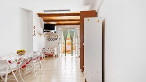 A dining area with a table set for four, a refrigerator, and a kitchen visible through an open door.