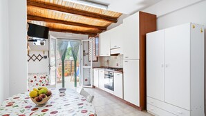 A kitchen with white cabinets, a wooden ceiling, and a dining area with a table set for two.