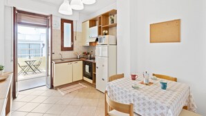Una cuina compacta amb zona de menjador, nevera, microones i taula petita amb caires.