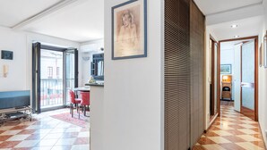 Ein Hotelzimmer mit kariertem Boden, einem Essbereich mit Stühlen, einem Fernseher und einem großen Fenster.