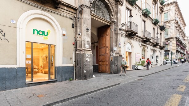 Ein Schaufenster mit modernem Design, ausgestattet mit einem Glastürschritt und einem Schild mit dem Logo "nau".
