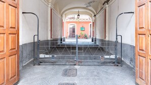 Ein Korridor mit einem Metallgitter, Holztüren und Blick auf ein Gebäude mit einer grünen Schilder.