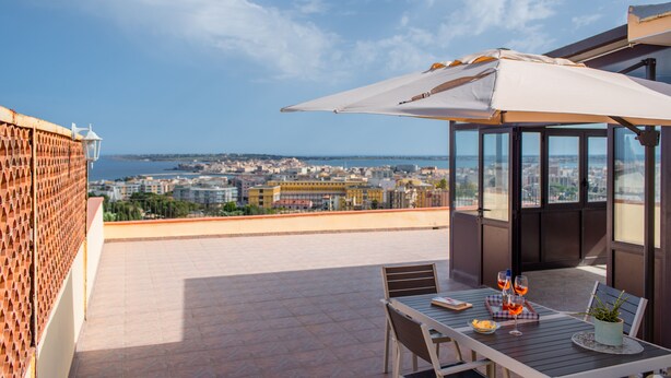 A terrace with a table, chairs, and a large umbrella. - La Terrazza Di Siracusa - Roomy And Bright Flat (Syracuse)